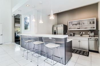 A modern kitchen with a bar area and three bar stools.